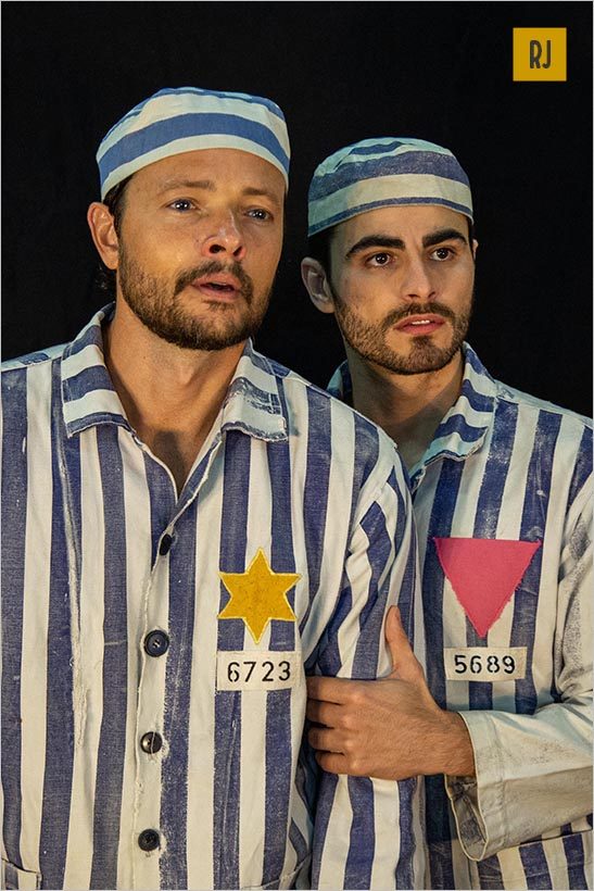 Na imagem dois homens vestidos de presidiários olham para frente como se estivessem observando algo. Foto: Pablo Henriques