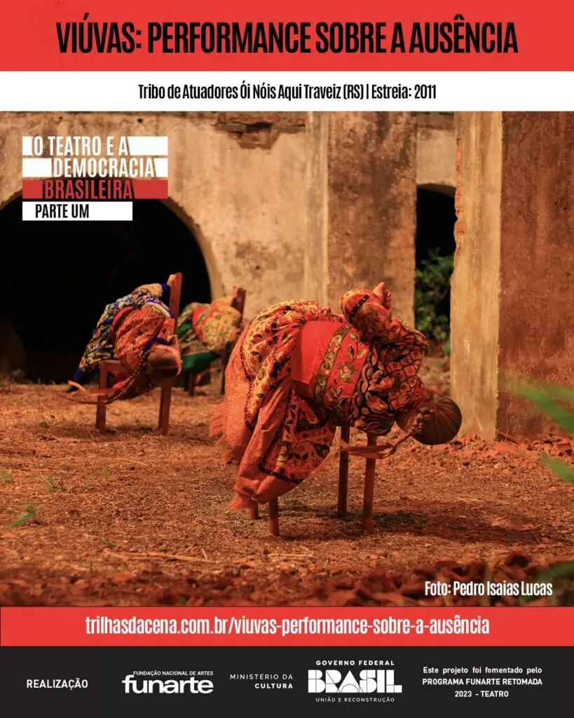 Três mulheres com roupas coloridas se inclinam com seus corpos sobre cadeiras. A cena externa na grama seca e algumas plantas é emoldurada por ruínas. Texto promove Viúvas: Performance Sobre a Ausência da Tribo de Atuadores Ói Nóis Aqui Traveiz.